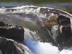 Water flowing over rocks creating a small waterfalls Stock Footage