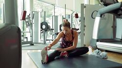 Woman stretching leg on gym exercise mat Stock Footage