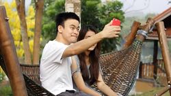 Smiling couple taking selfie on their phone in a park Stock Footage