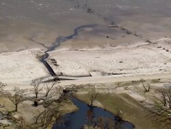 Aerial oil slick running from flooded neighborhood area to white sand beach / Waveland, Mississippi Stock Footage