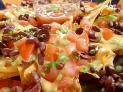 CU diced chives sprinkled over party platter loaded with nachos Stock Footage