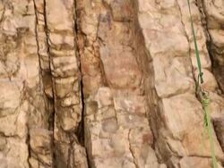Tilt shot of a rock-climber pulling up his partner's rope. Stock Footage