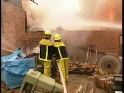 MS zooming out to WA, Fire fighters hosing down burning warehouse Stock Footage
