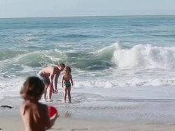 MS PAN Man and girl hold hands then step into  ocean while boy carries water balloon to them and throws it at man / Montezuma, Puntarenas, Costa Rica Stock Footage