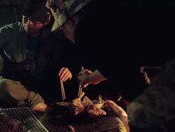 MS PAN Shot of friends cooking food at camp site in night / Okutama, Tokyo, Japan Stock Footage