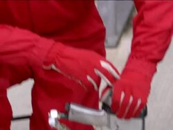 Medium shot pit crewman wearing headsets and goggles / tilt down gloved hand holding lug gun Stock Footage