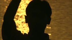 A Diwali celebrant waves long grasses on the banks of a golden river in India. Stock Footage