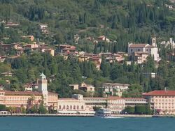 WS View of ancient luxury hotels on edge of lake and village climbing up hill / Gardone Riviera, Brescia, Italy    Stock Footage