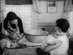 B/W 1934 nurse bathing baby in home as mother with other baby watches / WPA project / newsreel Stock Footage