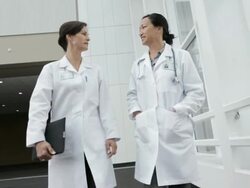 MS POV Two female physicians walking along hospital corridor and talking / Seattle, Washington, USA Stock Footage