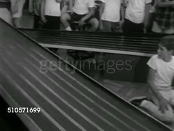 1965: SLOT CAR RACING: VS Miniature cars on track, TRACKING Cars racing, VS Young pre-teen boys, teenagers & adults in room watching, responding to race, one 'crashed' car being turned back over. Die-cast, plastic, hobby, fad, Iconic 1960s. Instructional Video