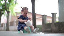 baby girl sitting on a potty outdoors and holding toilet paper Stock Footage