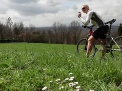 Bicycling couple take pictures of descent thru grasses Stock Footage