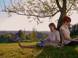 Mother and daughter relaxing under a tree Stock Footage