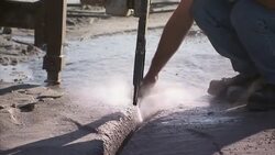 A quarry worker uses water spraying from a drill bit to rinse off a nail. Stock Footage