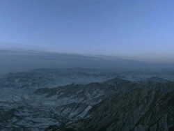 A view from The Great Wall of China of mountains lightly dusted with snow, with a moon high in the sky.  Stock Footage