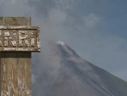 Mayon volcano smoulders behind religious sign on cross, Philippines, Dec 2009 Stock Footage
