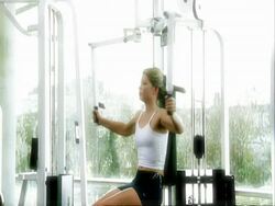 MS young woman on weight machines, zoom out Stock Footage