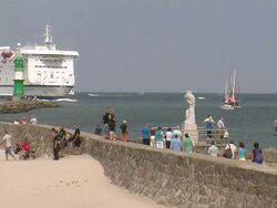 WS People walking on beach with ferry ship moving on river / Warnemuende near Rostock, Mecklenburg-Western Pomerania, Germany Stock Footage