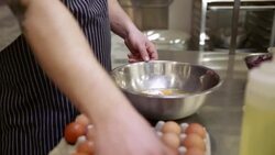 Close up of chef cracking eggs into bowl in commercial kitchen Stock Footage