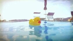 Yellow rubber duck floating in a swimming pool Stock Footage
