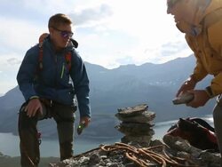 Mountaineers build rock cairn on mtn summit together Stock Footage