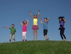 Diverse group of kids jumping on hill in slow motion Stock Footage