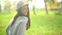 Woman in a hat walking through the park Stock Footage