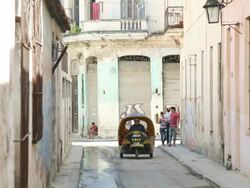 MS Shot of Havana side street with Coco Taxi and Pedestrians / Havana, Cuba  Stock Footage