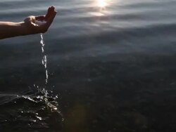 Pan downwards to hands scooping clean water from lake Stock Footage