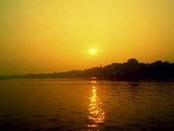 Wide shot Ganges River with silhouetted city in background at sunset / Varanasi, India Stock Footage