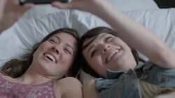 Two young women take selfies with smartphone in bed Stock Footage