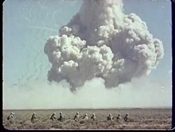 1950s MONTAGE CU Soldier looking up at sky and mushroom cloud / PAN from back of helmet to mushroom cloud / MS Two soldiers looking up at sky / PAN Mushroom cloud forming at Camp Desert Rock at Nevada Test Site / Nye County, Nevada, USA Stock Footage
