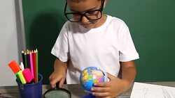Boy looking through magnifying glass at globe Stock Footage