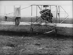 B/W 1910s REAR VIEW Glenn Curtiss taking off in early airplane with group of men watching Stock Footage
