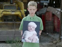 Slow motion of boy showing photo of himself as baby with cleft palate. Stock Footage