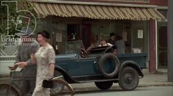 Man loading automobile outside storefront, 1930s - reenactment Stock Footage