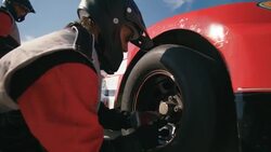 Stock car pit-crewman tightens new race-car tire lug-nuts Stock Footage