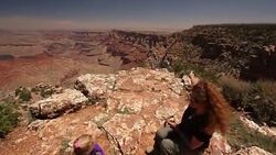 Mother talks to her young daughter on the rim of the Grand Canyon and points over edge Stock Footage