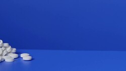 Pile of white pills on blue background Stock Footage