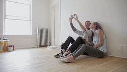 Couple taking selfie on hardwood floor in new house Stock Footage