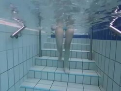 Young woman in blue bikini stepping into swimming pool Stock Footage