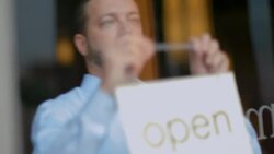 Small business owner hangs Open sign on restaurant door Stock Footage