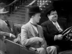 B/W 1931 tracking shot Stan Laurel + Oliver Hardy driving in convertible car with man in backseat / feature Stock Footage