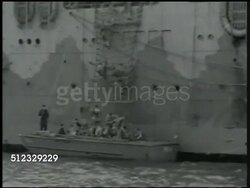 1942: U.S. MARINE CORPS: SHIP TO SHORE ASSAULT FORCE: MS Side of Navy battle ship. MS Light military tank being lifted by crane on side of ship. WS Soldiers climbing down net to transport boat. HA VS Marines down net into boat. Amphibious warfare. Instructional Video