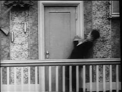 B/W 1916 Charlie Chaplin ducking + entering doorway after being knocked over by swinging pendulum Stock Footage