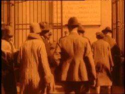 Immigrants walk out of an Ellis Island building and board a ferry. News Clip