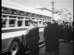 B/W 1942/3 REAR VIEW bus with Japanese-Americans for deportation leaving as neighbors wave good-bye Stock Footage