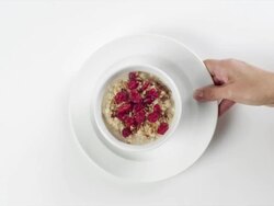 CU Woman hand entering setting down round white bowl with oatmeal and raspberries breakfast / Omaha, Nebraska, United States Stock Footage