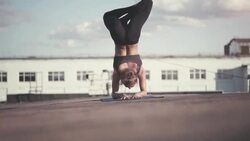 Young woman doing yoga meditating outdoors on a rooftop at sunset Stock Footage